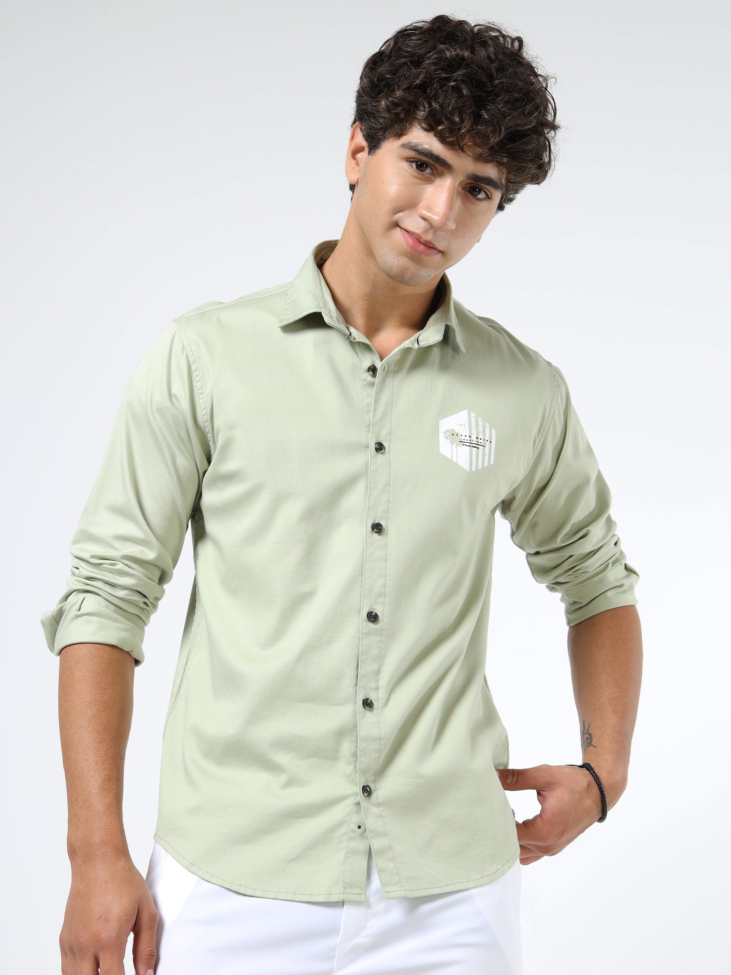 Man wearing a light green shirt with a logo on a white background