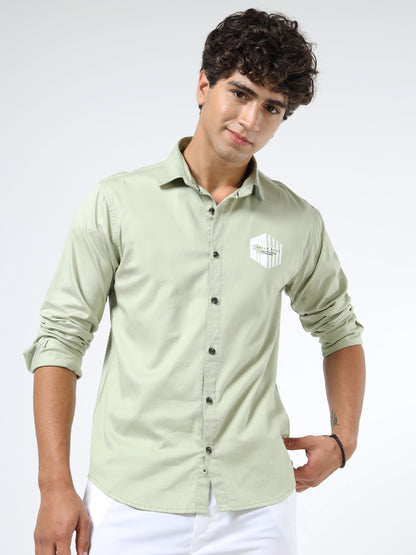 Man wearing a light green shirt with a logo on a white background