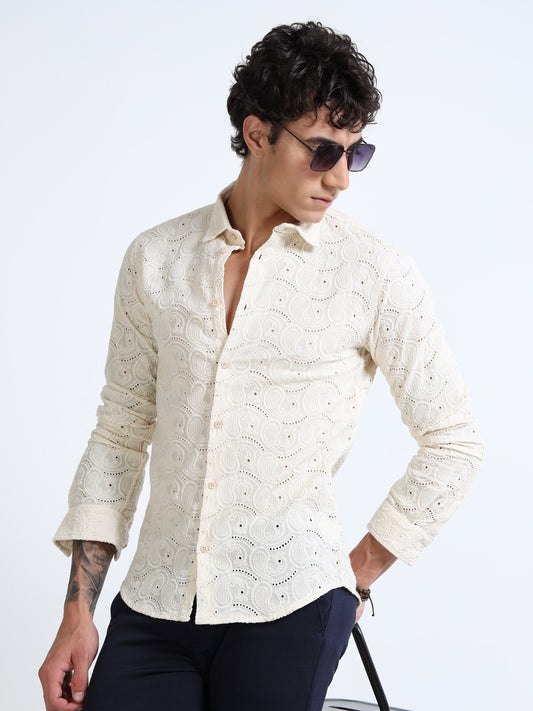 Man wearing a cream embroidered shirt and sunglasses on a white background