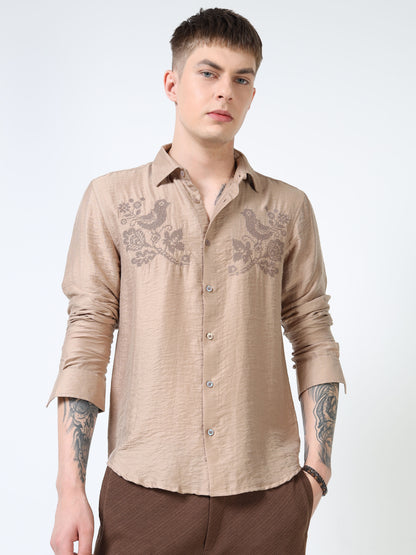 Man wearing a beige embroidered shirt on a white background