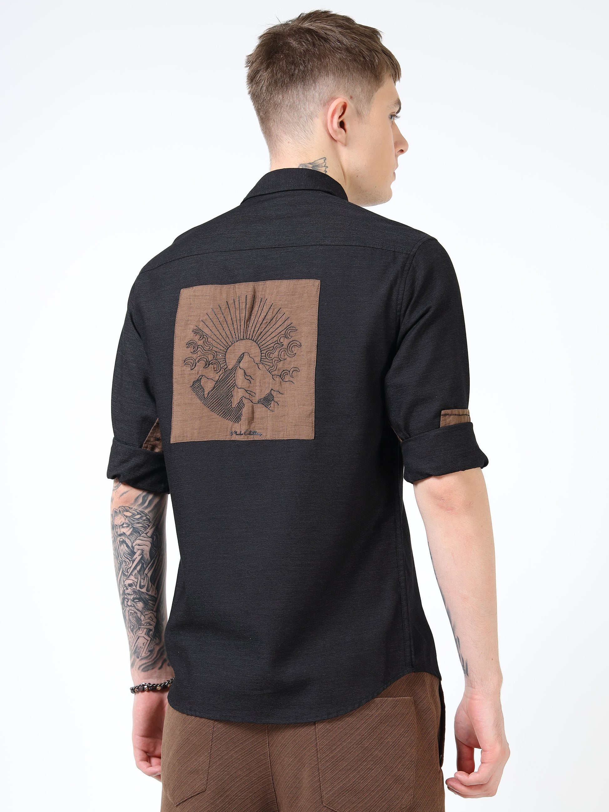 Man wearing a black shirt with a brown graphic on the back against a white background
