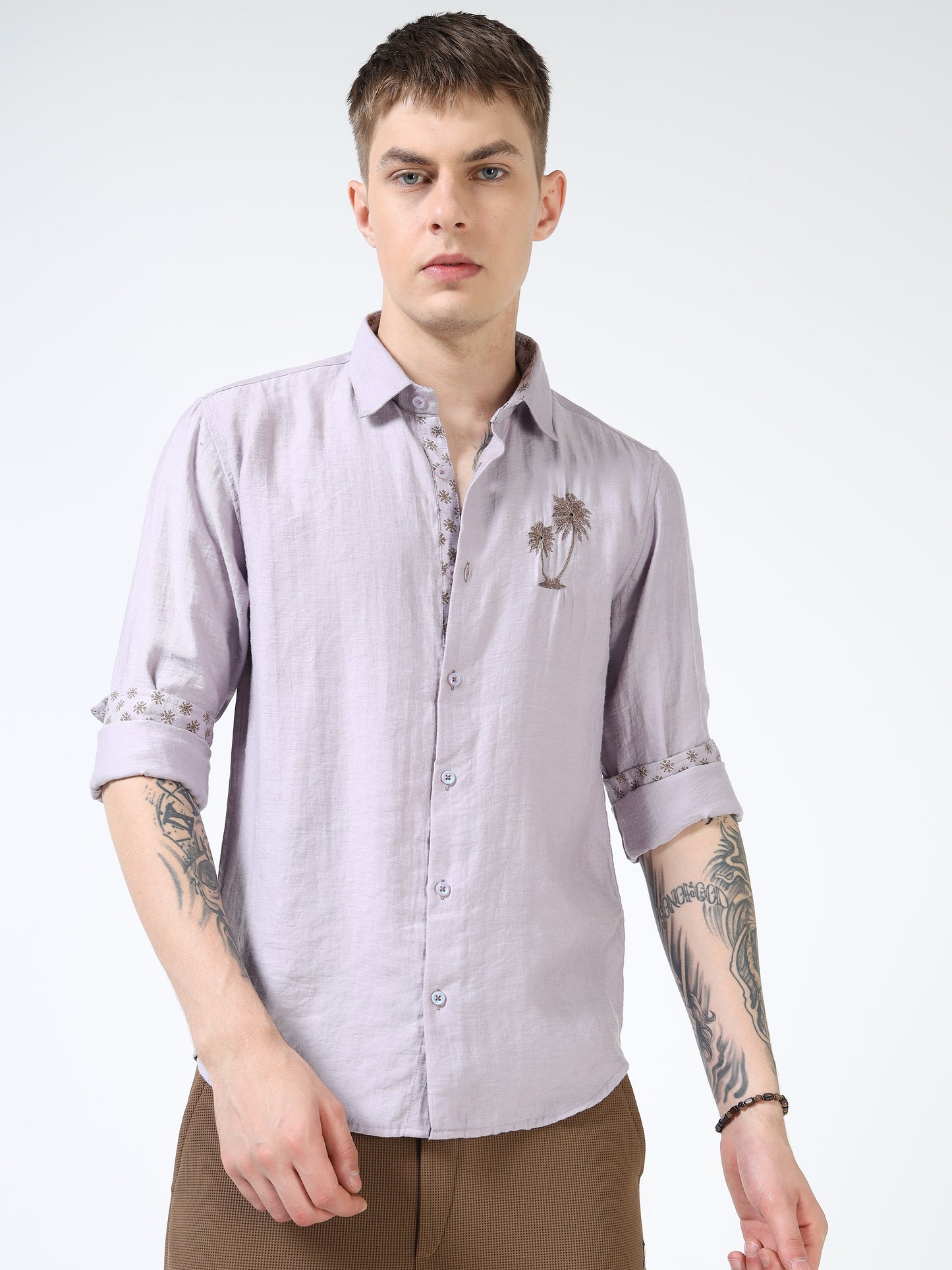 Man wearing a light purple button-up shirt with a palm tree design on a white background