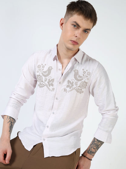 Man wearing a white embroidered shirt on a light gray background